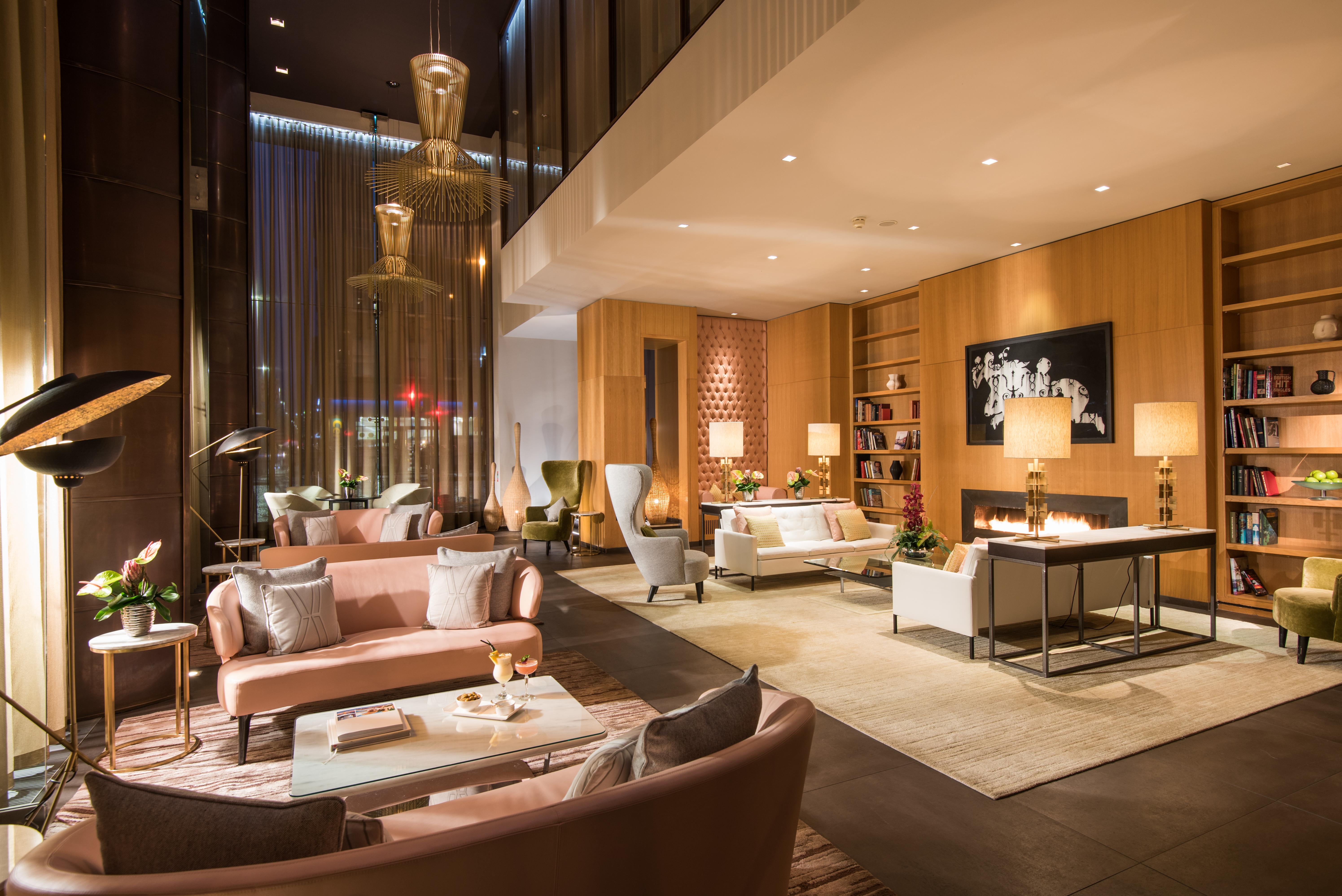 The Fitzwilliam Hotel Belfast Eksteriør bilde The photo shows a modern and elegant lobby or lounge area. The space features a mix of contemporary and cozy furniture, including light-colored sofas and armchairs arranged around small tables. There are decorative elements like vases with flowers, a